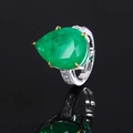 Detailed close-up of a pear-cut emerald zircon ring with brilliant sparkle on black background - Emerald Green