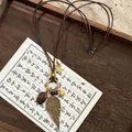 Collier bohème en perles de bois avec plumes en bronze et étoile, long de 68 cm réglable - Style Grande Plume Dorée