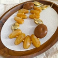 Detalle del collar de acrílico ámbar y cuentas doradas en una bandeja de madera con tela - Estilo de cuentas grandes / Collar oro y café