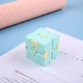 Mint green and beige infinity cube sensory fidget toy for stress relief on a book - Green