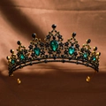 Detail of golden crown with black gems and emerald teardrop stones on brown cloth - Antique Green