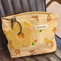 Dettaglio della borsa trucco in tela beige con motivo orso e ciondolo a fiore giallo - Orso Carino Grande (Beige Cartone) / Grande