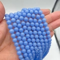 Detailed view of sky blue luminous round beads held by hand for jewelry DIY size reference - Blue Luminous Stone