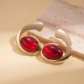Detalle de pendientes dorados con piedras rojas profundas sobre fondo de piedra natural - Grande / Dorado/Rojo