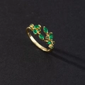 Detail of gold leaf ring featuring marquise-cut emerald green stones on black background - Leaf Branch Style