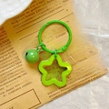 Detail of green star keychain with mini bell on vintage newspaper background - Green