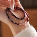 Detail of garnet beaded bracelet with gold accents on model wearing white sweater - Garnet Strawberry Quartz Double Loop Bracelet (Exquisite Gift Box)