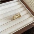 Dettaglio di un anello a stella dorato a tre strati con zirconi su un cuscino per gioielli - Oro
