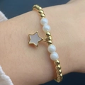 Detail of beaded star charm bracelet featuring gold beads and white star pendant - Mother-of-pearl Star