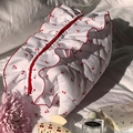 Quilted floral makeup bag with red cherry pattern and ruffle trim on white bedding - Cherry Ruffle Style