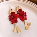 Retro-Ohrringe in Fischform mit goldenem Hammermetallkopf und roten Pailletten-Schuppen. - Rot