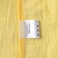 Detail of 100% cotton fabric texture and care label on a yellow V-neck skirt set - S / 100% Cotton Yellow