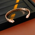 Dettaglio del bracciale rigido oro rosa con zirconi e texture incrociata plissettata - Oro rosa