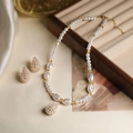Detailed view of elegant pearl necklace and stud earrings set with gold metal accents - Gold Pearl Teardrop Set