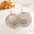 Gros plan de boucles d'oreilles argentées évidées avec des fleurs séchées naturelles - Grand Cercle Motif Rétro Ajouré
