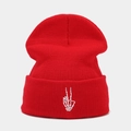 Detail of red knitted beanie featuring white skull hand peace sign embroidery on the cuff - Red