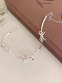 Detail of silver snake chain bracelet featuring three polished bow charms and a lobster clasp - Silver