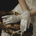 Elegant white short satin bridal gloves with pearl trim resting on a vintage mirror - Satin 3-Row Pearl