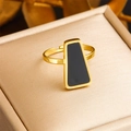 Anello in acciaio dorato con pietra geometrica nera su un cuscino per portagioielli - Stile Trapezio Nero (R458)
