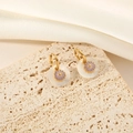 Elegant gold titanium steel shell flower earrings displayed on beige travertine stone - Gold Purple