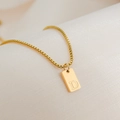 Dettaglio macro del ciondolo quadrato placcato oro 18K con lettera D su seta beige - Lettera D
