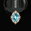 Detailed macro view of an oval blue gemstone pendant with a golden ornate frame - Sky Blue