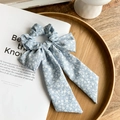Detailed shot of a blue floral scrunchie with long ribbon tails on a magazine - Daisy Blue
