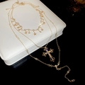 Gros plan d'un collier doré multicouche avec étoiles et pendentif croix en strass brillants - Or (Ensemble de 3 pièces)
