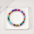 Colorful cylindrical bead bracelet displayed on a square clear acrylic jewelry stand - Acrylic Small Square Display Tray