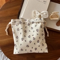 Detailed texture of cotton floral drawstring pouch on a warm wooden home desk - Beige Base Brown Small Floral