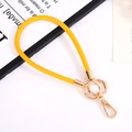 Close-up of yellow PU leather wrist strap keychain with golden metal spring ring clasp - Turmeric