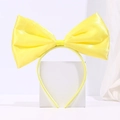 Detail of a bright yellow satin bow headband displayed on a white minimalist pedestal - Yellow