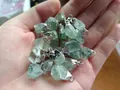 Raw green fluorite stone pendants with silver metal loops in hand for size visualization - Green Fluorite