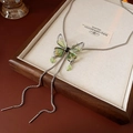 Detail of a green enamel butterfly bolo necklace with rhinestones on a wooden tray - Necklace - Silver - Green