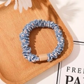 Close-up of blue floral scrunchie with orange dots and brown resin buckle detail - Satin Floral Blue