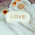 Plush white faux rabbit fur sleep mask with gold LOVE embroidery on a cozy bed - LOVE Embroidery / White