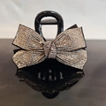 Macro di una molletta per capelli nera con strass scintillanti su superficie lucida - Strass Champagne