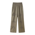 Detail of olive satin wide-leg trousers featuring intricate floral beadwork and embroidery - XS / Bottoms / Green