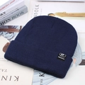 Detailed knit texture of navy blue winter beanie with rectangular decorative logo tag - Blue (TF Label)
