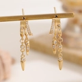 Macro shot of gold layered hoop earrings with dangling zircon fringe and metal spikes - Triple-Layer Semicircle Zirconia Stud Style (5888) / KC Gold