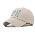 Close-up of green embroidered M letter on beige cotton baseball cap with fine stitching - Beige