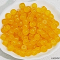 Detailed view of 6x8mm yellow translucent resin barrel beads in a white ceramic dish - Topaz Yellow