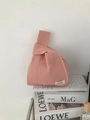 Detail of pink knitted knot bag featuring a honeycomb hollow texture and brand label - Lotus Pink