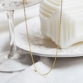 Close-up of a gold stainless steel chain hanging on glass showing fine metal texture - Gold Bead Chain