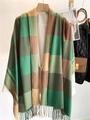 Dettaglio della sciarpa a quadri tipo cashmere con frange su una gruccia di legno - Quadri Verde Marrone Giallo