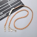 Detail of a brown leather woven chain with white pearls and camellia flower pendant charms - Crossbody Chain / Tan