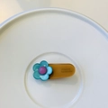 Detailed close-up of blue floral hair clip with FRANCE Handmade engraved text on back - Light Brown with Blue Green Flower