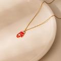 Christmas necklace in gold with a red and white heart glove pendant on a ceramic dish - Heart Christmas Glove Necklace