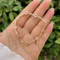 Detail of pink heart-shaped gems and gold chain with fine zircon stones on model's hand - Pink