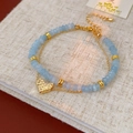 Dettaglio di un bracciale a doppio strato con perline azzurre, catena dorata e cuore - Bracciale a Doppia Fila con Perline Blu (Ciondolo a Cuore)